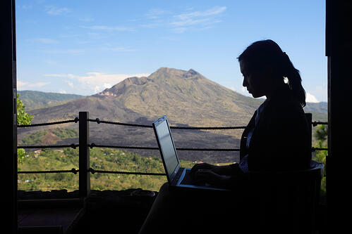 person sitting with a laptop landscape behind them